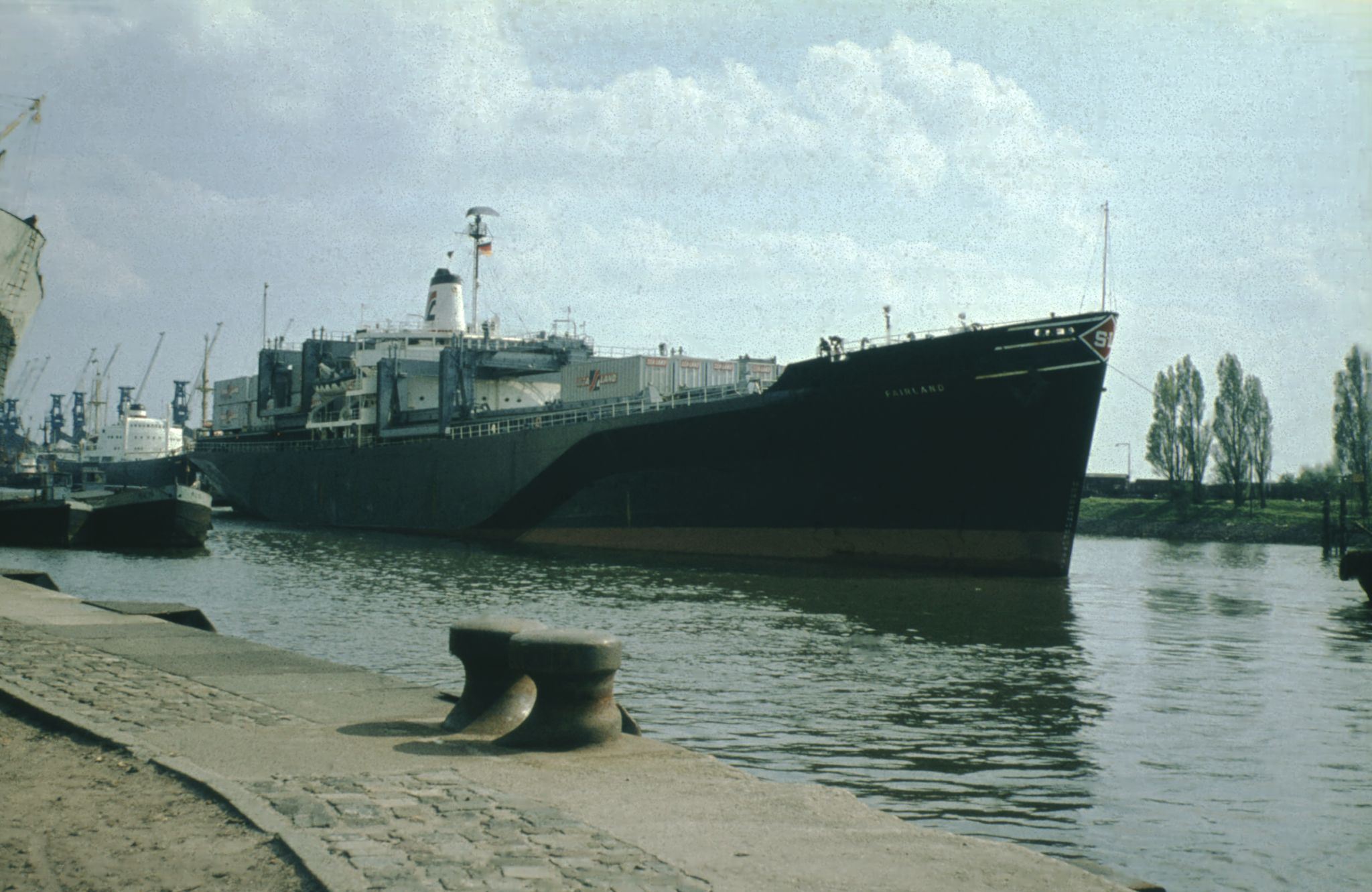 The Sea-Land container ship Fairland moored at Bremen’s Überseehafen in 1966, its deck stacked with Sea-Land intermodal containers and harbour cranes lining the quay behind it.
